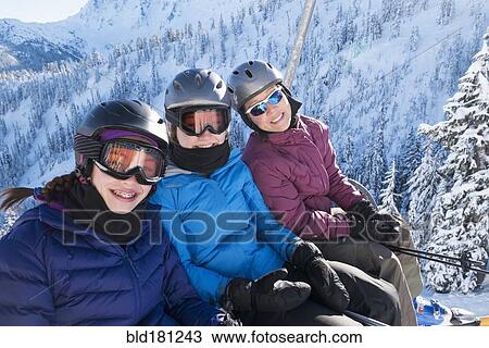 Stock Image - Mother and daughters riding ski lift. Fotosearch