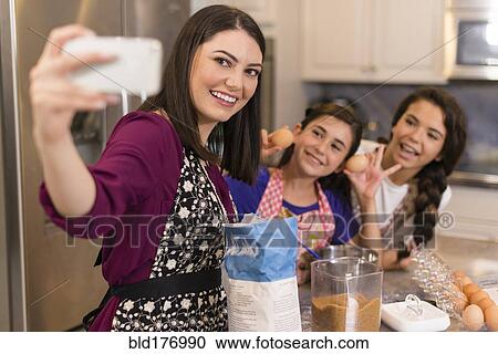 Mother and daughters taking selfie in kitchen View Large Photo Image Stock Image - Mother and daughters taking selfie in kitchen. Fotosearch