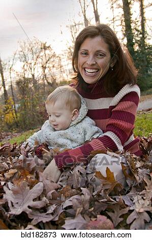 Mother and son sitting in autumn leaves View Large Photo Image Stock Image - Mother and son sitting in autumn leaves. Fotosearch