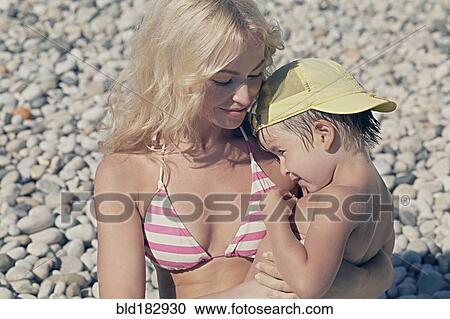 Mother holding son on rocky beach View Large Photo Image Stock Image - Mother holding son on rocky beach. Fotosearch