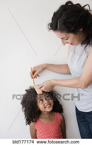 Mother measuring height of daughter against wall View Large Photo Image Picture - Mother measuring height of daughter against wall. Fotosearch