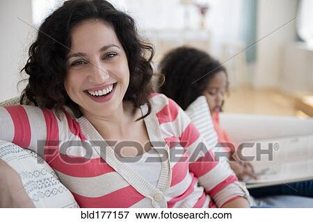 Mother smiling on sofa with daughter View Large Photo Image Stock Photo - Mother smiling on sofa with daughter. Fotosearch
