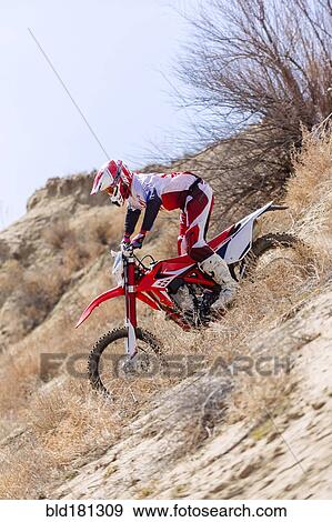 Stock Photo - Motorcyclist riding dirt bike in remote field. Fotosearch