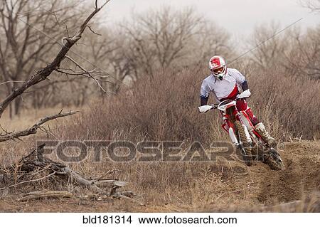 Picture - Motorcyclist riding dirt bike on rural path. Fotosearch