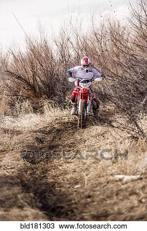 Stock Image - Motorcyclist riding dirt bike on rural path. Fotosearch