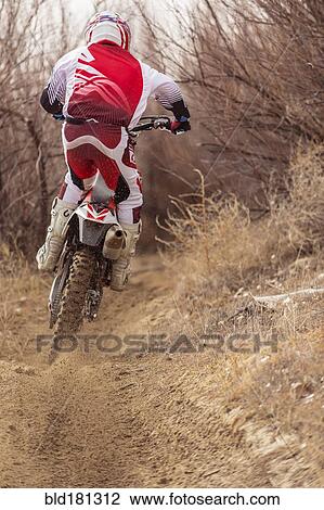 Stock Image - Motorcyclist riding dirt bike on rural path. Fotosearch