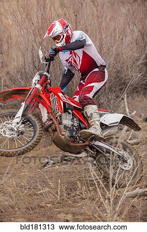 Stock Image - Motorcyclist riding dirt bike on rural path. Fotosearch