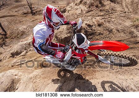 Stock Photo - Motorcyclist riding dirt bike on hillside. Fotosearch