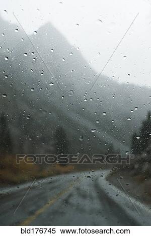 Stock Photography - Mountains and rural road through wet window. Fotosearch