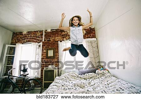 Stock Photo - Native American girl jumping on bed. Fotosearch