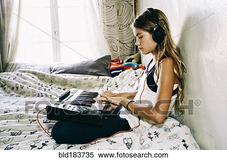 Stock Photography - Native American girl playing keyboard on bed. Fotosearch