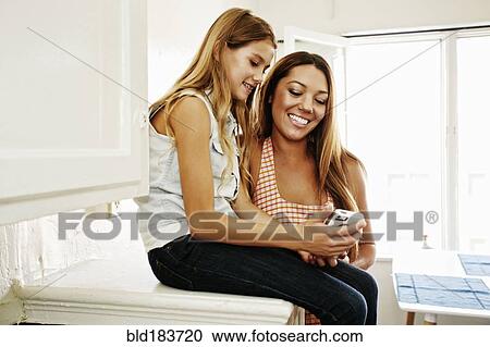 Stock Image - Native American mother and daughter using cell phone. Fotosearch