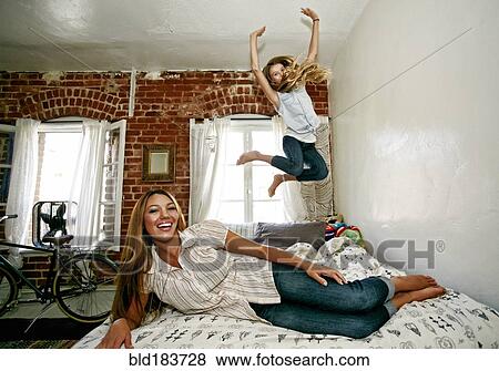 Native American mother and daughter jumping on bed View Large Photo Image Stock Photo - Native American mother and daughter jumping on bed. Fotosearch