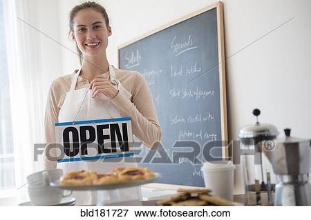 Stock Photo - Native American woman holding open sign in cafe. Fotosearch