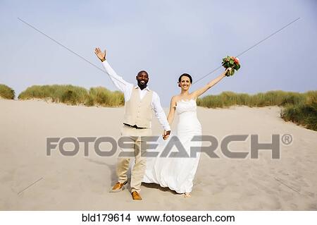 Picture - Newlywed couple cheering on beach. Fotosearch