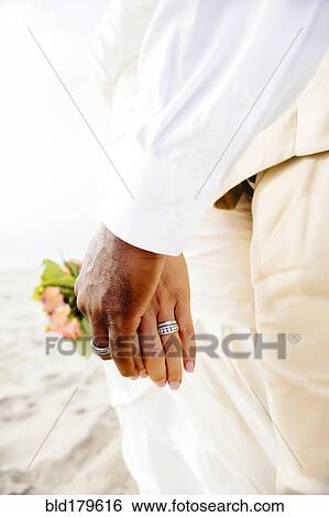 Stock Photograph - Newlywed couple holding hands on beach. Fotosearch