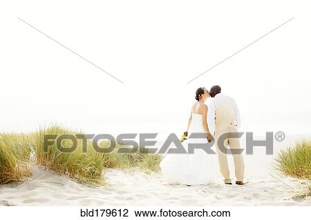 Stock Image - Newlywed couple kissing on beach. Fotosearch