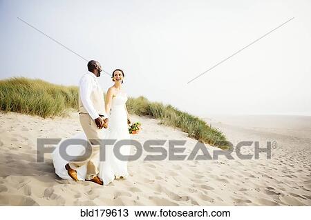 Stock Image - Newlywed couple walking on beach. Fotosearch