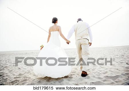Stock Photography - Newlywed couple walking on beach. Fotosearch