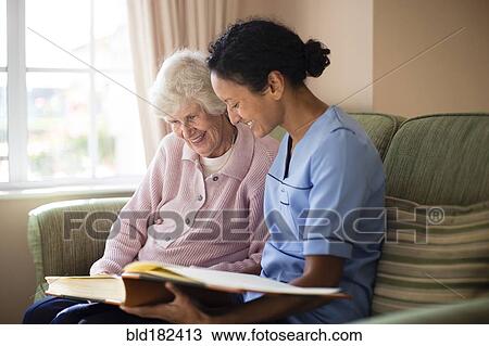Stock Image - Nurse and patient looking at photo album. Fotosearch