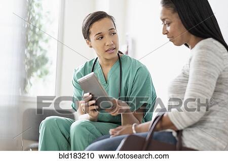 Stock Image - Nurse and patient using digital tablet. Fotosearch