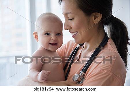 Picture - Nurse holding baby girl in hospital. Fotosearch