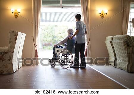 Stock Photograph - Nurse pushing patient in wheelchair. Fotosearch