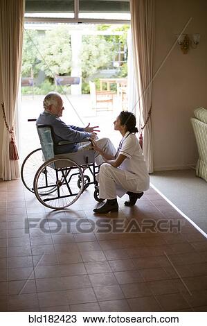 Stock Image - Nurse talking to patient in wheelchair. Fotosearch