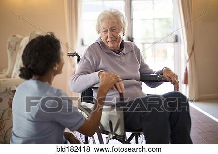 Stock Photo - Nurse talking to patient in wheelchair. Fotosearch
