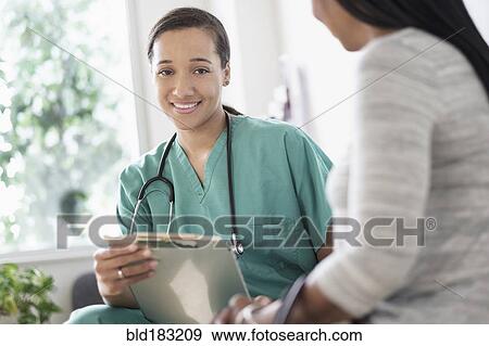Nurse with clipboard sitting with patient View Large Photo Image Stock Photo - Nurse with clipboard sitting with patient. Fotosearch