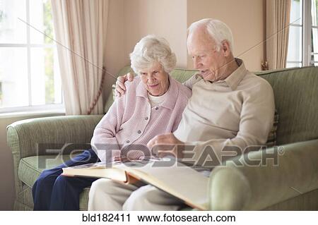 Stock Image - Older Caucasian couple looking at photo album. Fotosearch