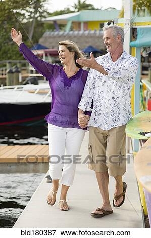 Stock Photo - Older Caucasian couple waving from pier. Fotosearch