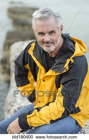 Stock Image - Older Caucasian man sitting outdoors. Fotosearch