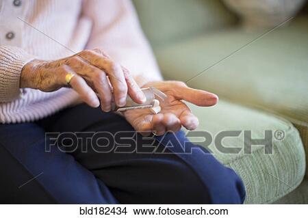 Picture - Older Caucasian woman holding medication. Fotosearch