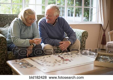 Stock Photo - Older couple on sofa solving jigsaw puzzle. Fotosearch