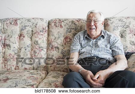 Stock Photo - Older man sitting on sofa. Fotosearch
