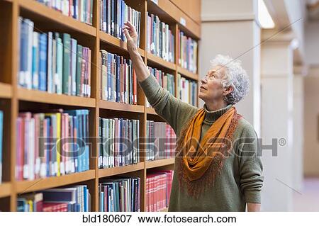 Older mixed race woman choosing book in library View Large Photo Image Stock Photo - Older mixed race woman choosing book in library. Fotosearch