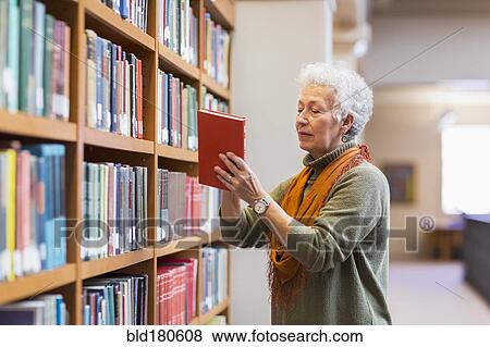Older mixed race woman choosing book in library View Large Photo Image Stock Photo - Older mixed race woman choosing book in library. Fotosearch
