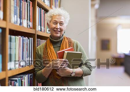 Older mixed race woman holding books in library View Large Photo Image Stock Image - Older mixed race woman holding books in library. Fotosearch