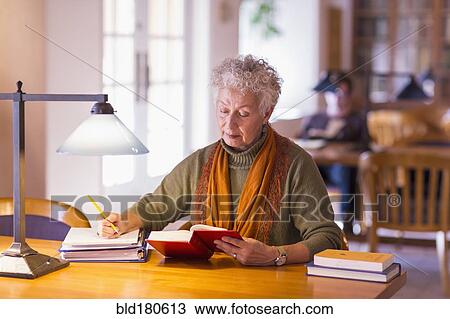 Older mixed race woman reading book in library View Large Photo Image Stock Image - Older mixed race woman reading book in library. Fotosearch