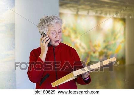 Stock Photo - Older mixed race woman talking on phone in art gallery. Fotosearch