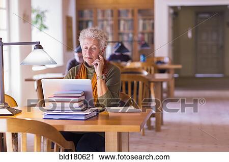 Older mixed race woman using laptop in library View Large Photo Image Stock Image - Older mixed race woman using laptop in library. Fotosearch