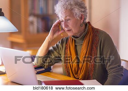 Older mixed race woman using laptop in library View Large Photo Image Stock Photo - Older mixed race woman using laptop in library. Fotosearch