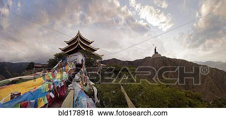 Stock Photo - Panoramic view of prayer flags and traditional building on mountain. Fotosearch