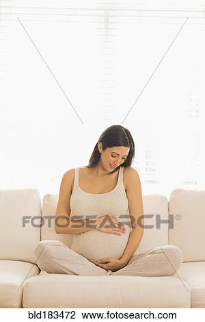Pregnant Caucasian woman sitting on sofa View Large Photo Image Stock Image - Pregnant Caucasian woman sitting on sofa. Fotosearch