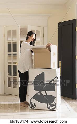 Pregnant Caucasian woman unpacking baby supplies View Large Photo Image Picture - Pregnant Caucasian woman unpacking baby supplies. Fotosearch