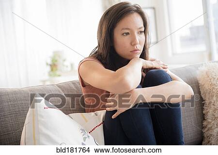 Sad mixed race woman sitting on sofa View Large Photo Image Picture - Sad mixed race woman sitting on sofa. Fotosearch