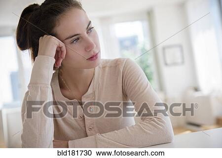 Stock Image - Sad Native American woman sitting at desk. Fotosearch