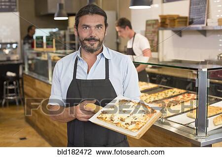 Stock Image - Server holding pizza in cafe. Fotosearch