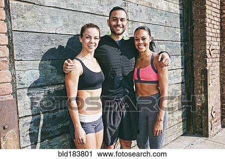 Stock Image - Smiling athletes hugging on sidewalk. Fotosearch